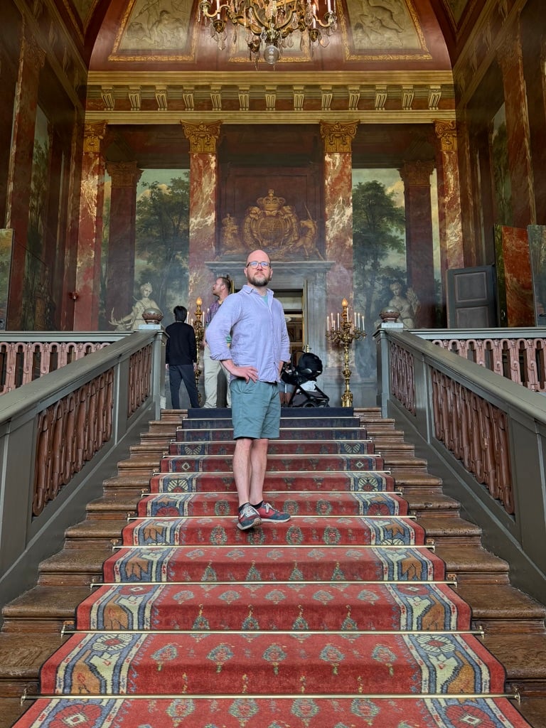 Heath striking a grand pose on an ornate staircase, in shorts.